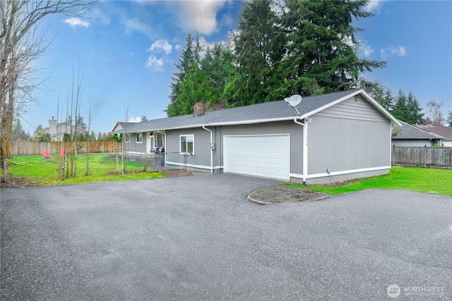 ranch-style home with driveway, an attached garage, a front lawn, and fence