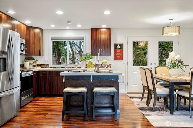 kitchen with a sink, wood finished floors, recessed lighting, stainless steel appliances, and light countertops