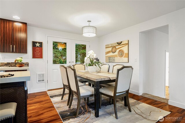 dining space with visible vents, wood finished floors, baseboards, and french doors