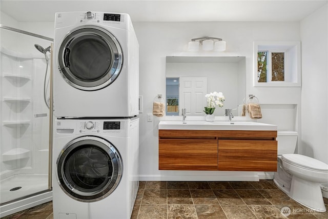 clothes washing area featuring laundry area, stacked washer and clothes dryer, and a sink