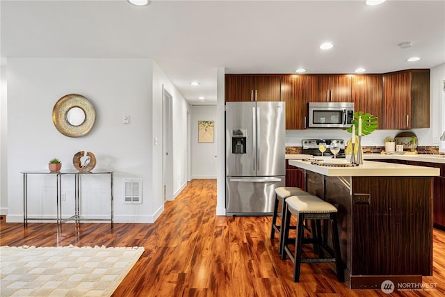 kitchen featuring visible vents, wood finished floors, recessed lighting, stainless steel appliances, and light countertops