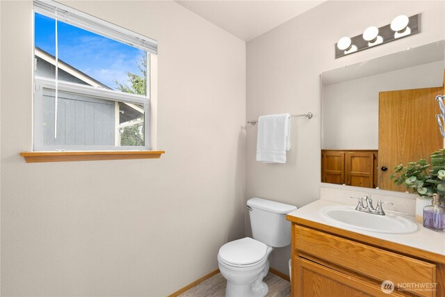 bathroom with toilet, vanity, and baseboards