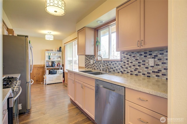 kitchen featuring tasteful backsplash, light wood-type flooring, appliances with stainless steel finishes, and a sink