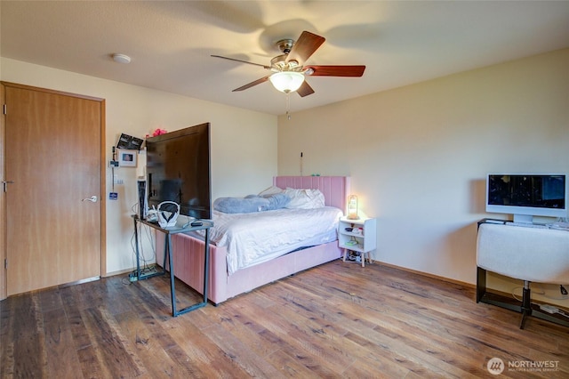 bedroom featuring a ceiling fan, baseboards, and wood finished floors