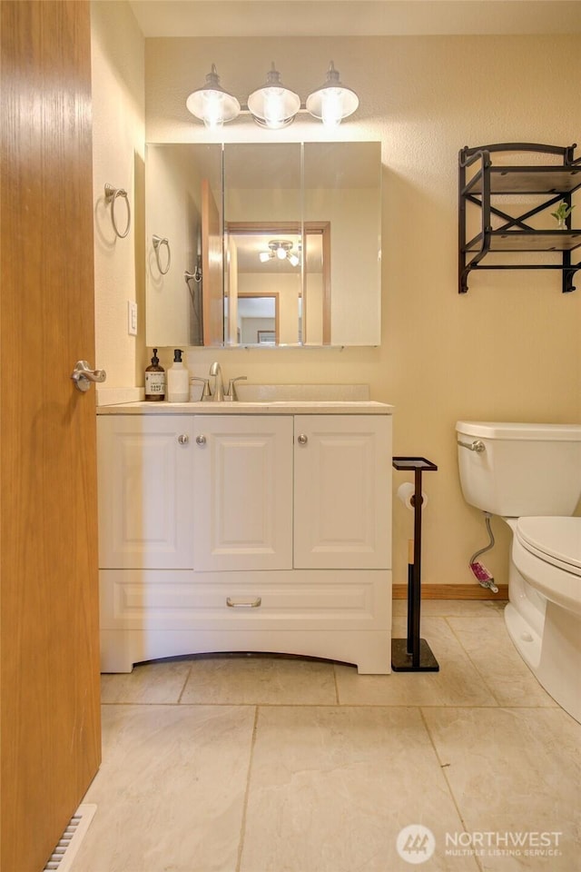 bathroom with tile patterned flooring, toilet, vanity, and baseboards