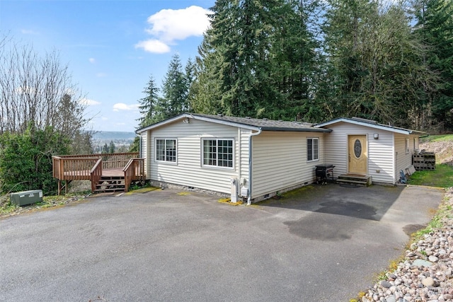 view of front of home with crawl space, a wooden deck, driveway, and entry steps