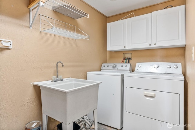 washroom with washing machine and clothes dryer, cabinet space, and a sink