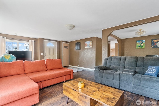 living area featuring a textured wall, arched walkways, baseboards, and wood finished floors