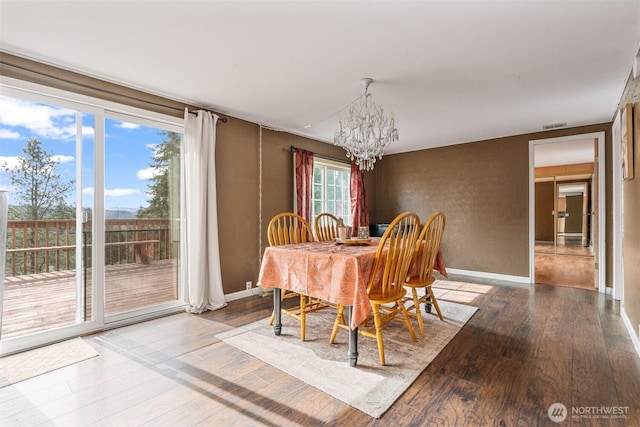 dining space featuring a chandelier, baseboards, visible vents, and wood finished floors