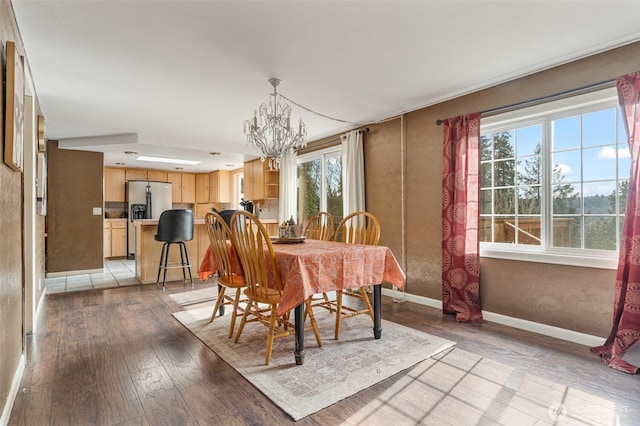 dining space featuring a chandelier, baseboards, and light wood-style floors