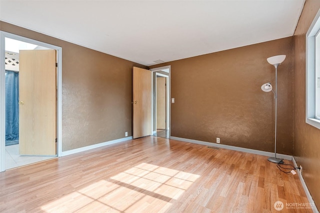 unfurnished room featuring visible vents, wood finished floors, and baseboards