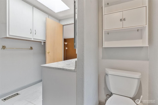 bathroom with vanity, a skylight, toilet, and visible vents