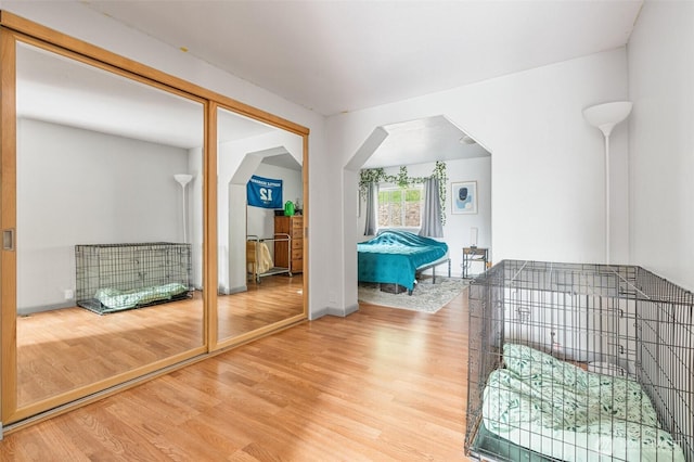 interior space with wood finished floors, arched walkways, and baseboards