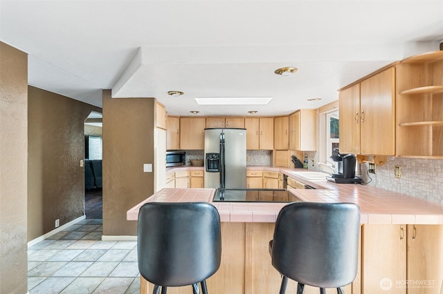 kitchen with decorative backsplash, appliances with stainless steel finishes, open shelves, and tile counters