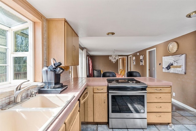 kitchen featuring tile countertops, light brown cabinets, a peninsula, a sink, and appliances with stainless steel finishes