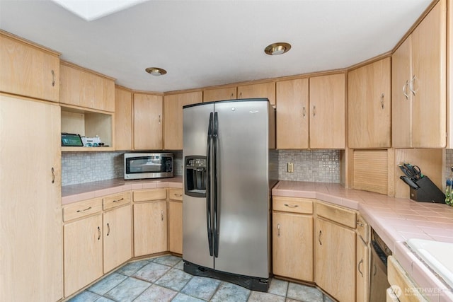 kitchen featuring tile countertops, stainless steel appliances, and light brown cabinetry