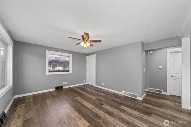 spare room featuring dark wood-style floors, visible vents, and a wealth of natural light