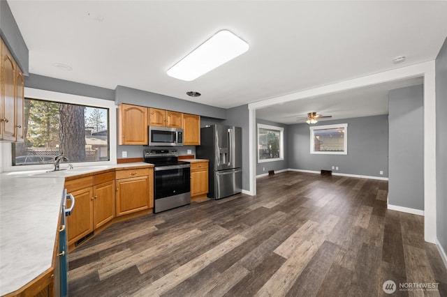 kitchen featuring baseboards, dark wood-style flooring, a sink, stainless steel appliances, and light countertops