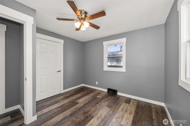 unfurnished bedroom with a ceiling fan, visible vents, baseboards, and dark wood-style flooring