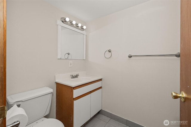 half bath featuring tile patterned flooring, toilet, vanity, and baseboards