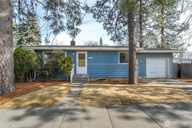 ranch-style home with entry steps, a garage, driveway, and a chimney