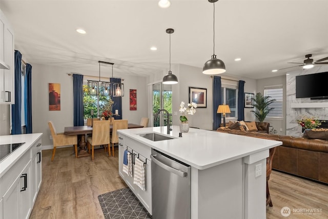 kitchen with white cabinetry, a sink, light countertops, stainless steel dishwasher, and open floor plan