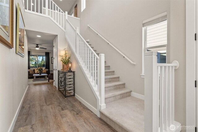 stairs with a towering ceiling, baseboards, and wood finished floors