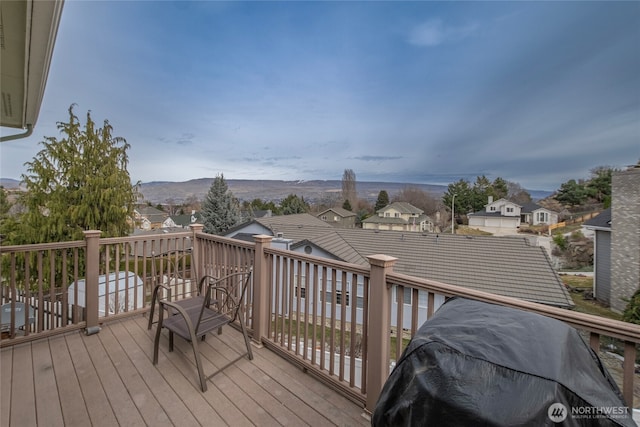 wooden deck featuring a residential view, a mountain view, and a grill