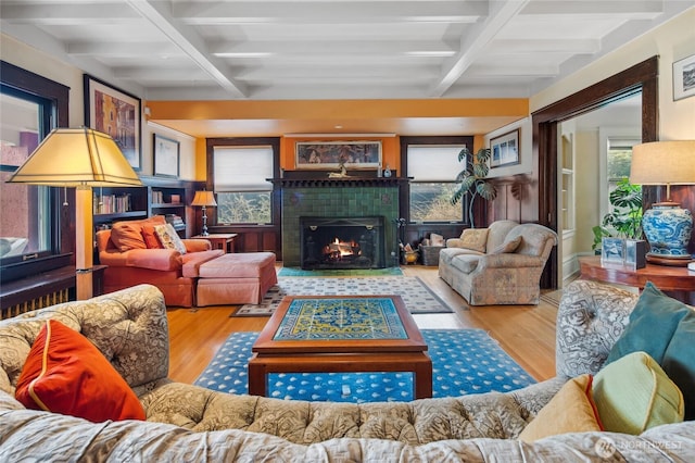 living room with beam ceiling, wood finished floors, coffered ceiling, and a tile fireplace