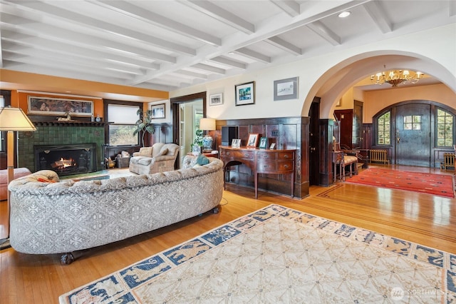 living room with beamed ceiling, a notable chandelier, wood finished floors, and a fireplace