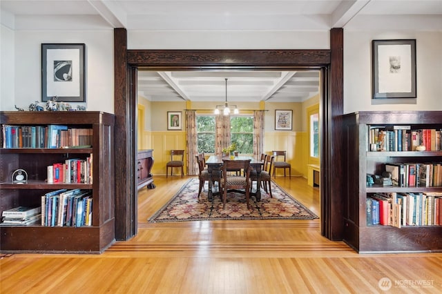 dining area featuring beam ceiling and a wainscoted wall