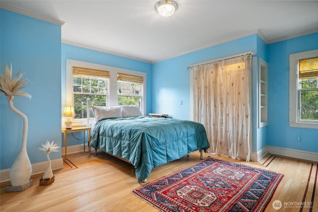 bedroom with multiple windows, wood finished floors, and baseboards