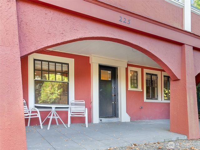 view of exterior entry featuring stucco siding and covered porch