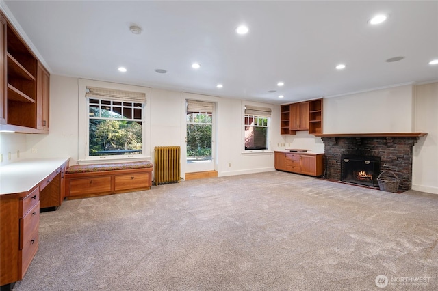 unfurnished living room featuring radiator, baseboards, light colored carpet, recessed lighting, and a fireplace