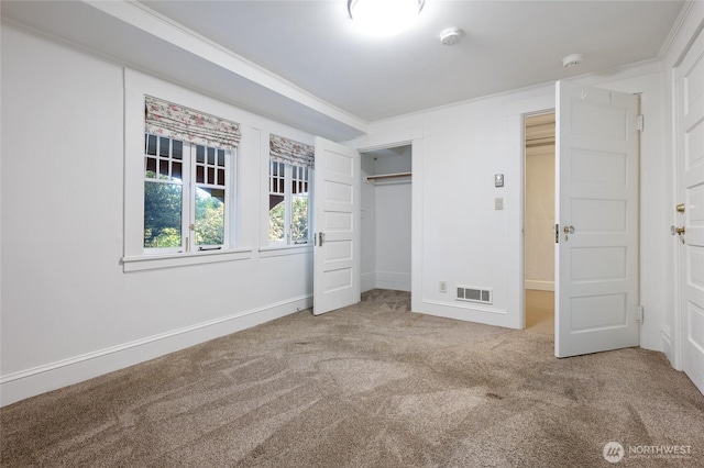 unfurnished bedroom featuring a closet, visible vents, crown molding, and carpet