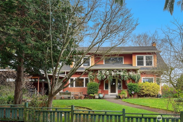 view of front facade with a fenced front yard, a chimney, and a front yard