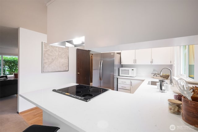 kitchen featuring a sink, freestanding refrigerator, stovetop, light countertops, and white microwave