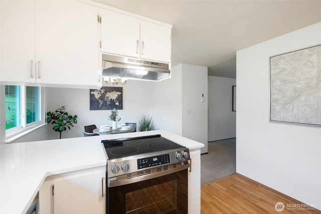 kitchen with stainless steel electric range oven, white cabinets, light countertops, and under cabinet range hood