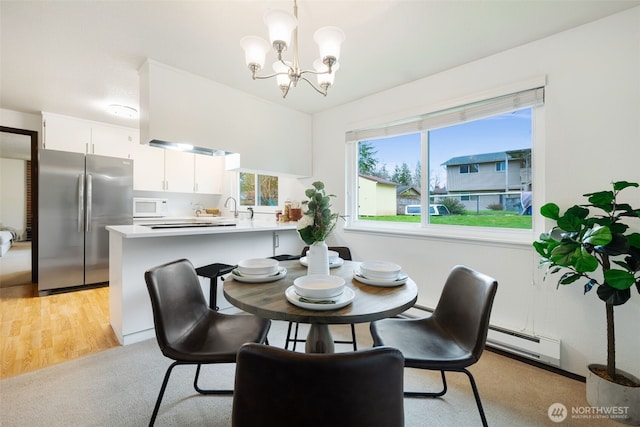 dining room with light carpet, a baseboard radiator, baseboard heating, and a chandelier