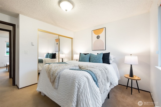 bedroom featuring light carpet, baseboards, a textured ceiling, and a closet