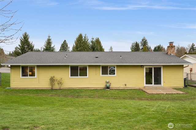 back of property with a lawn, a shingled roof, and a patio