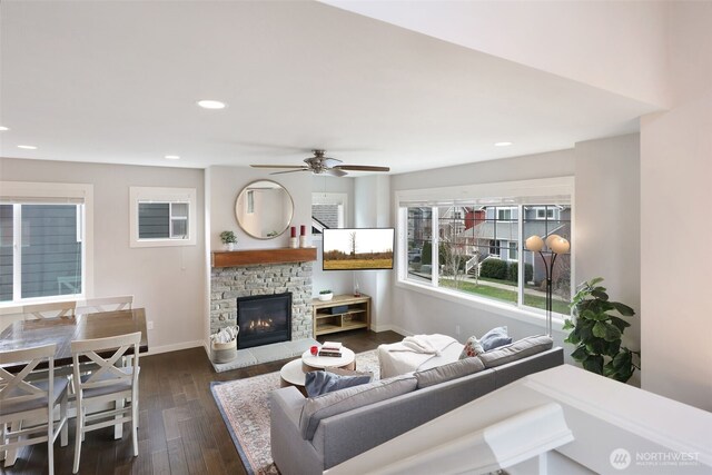 living room featuring dark wood-style floors, baseboards, a ceiling fan, a fireplace, and recessed lighting