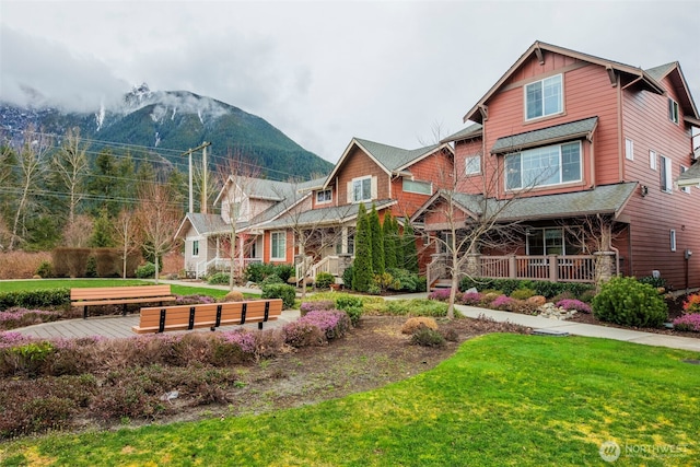 view of front of house featuring board and batten siding, a residential view, a porch, a front yard, and a mountain view