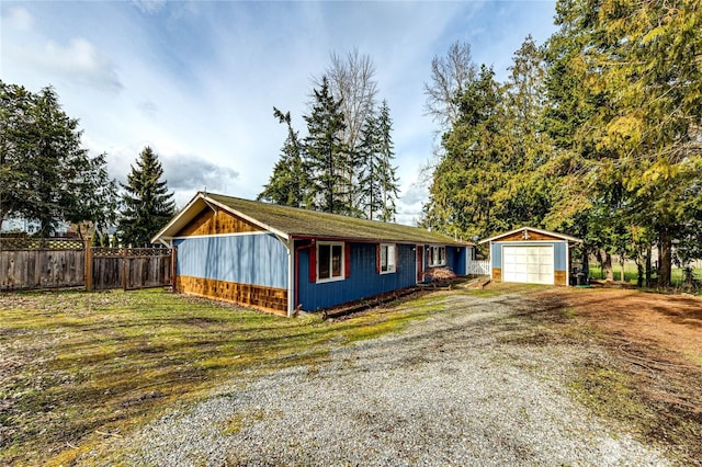 single story home featuring an outbuilding, driveway, a detached garage, and fence