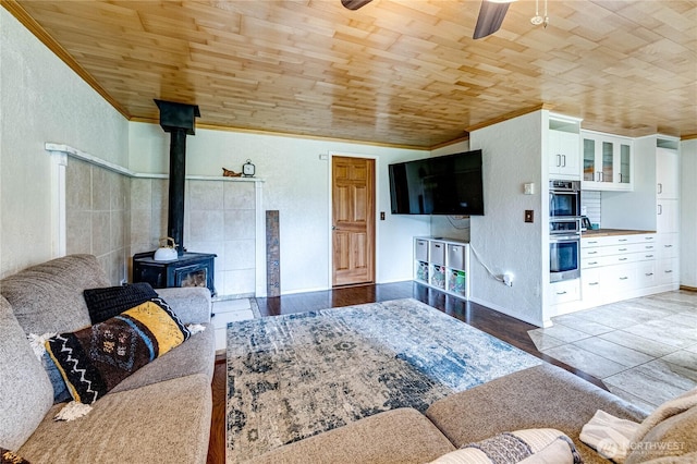 living room with wooden ceiling, a wood stove, and crown molding