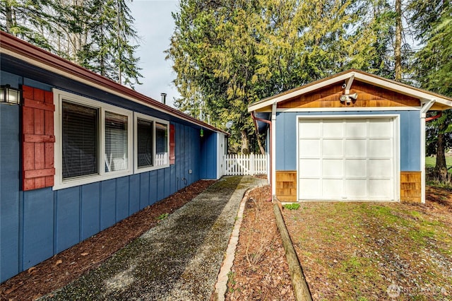 detached garage featuring fence and driveway