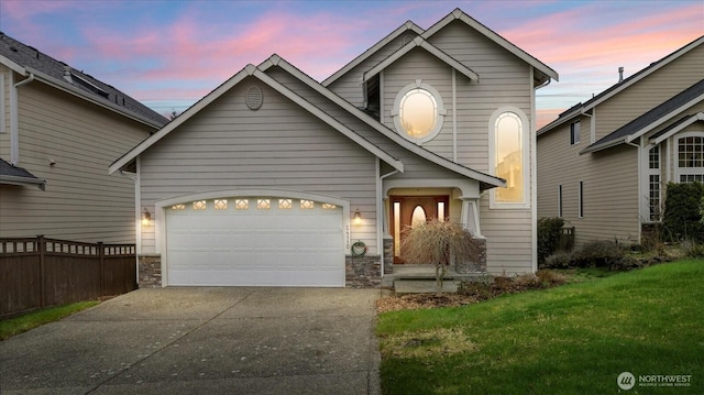 view of front facade featuring fence, concrete driveway, a front yard, a garage, and stone siding