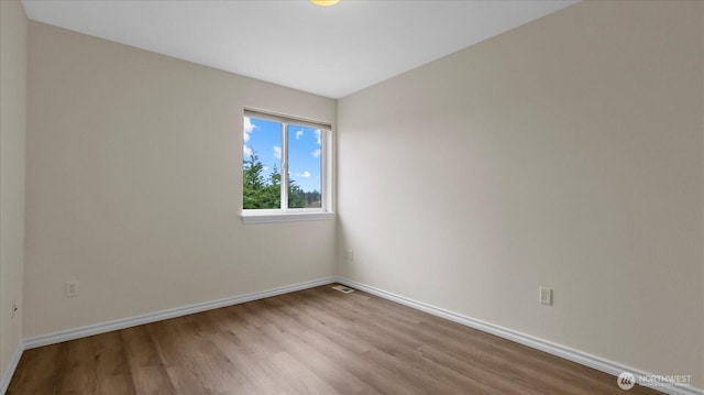 spare room with visible vents, baseboards, and wood finished floors