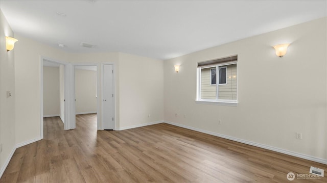 unfurnished room with light wood-type flooring, visible vents, and baseboards