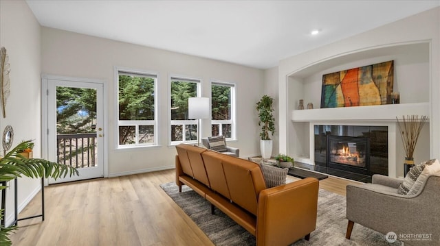 living area featuring a tiled fireplace, built in shelves, wood finished floors, and baseboards